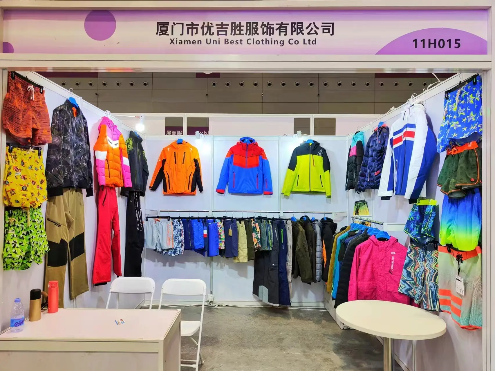 Colourful outdoor jackets and trousers displayed at a Uni Best exhibition booth